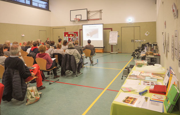 Lehrkräfte lauschen dem Vortrag, auf Tischen liegt Literatur bereit