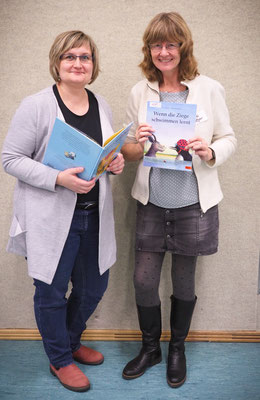 Lehrkräfte lesen Literatur, eine Lehrkraft zeigt das Buch "Wenn die Ziege schwimmen lernt"